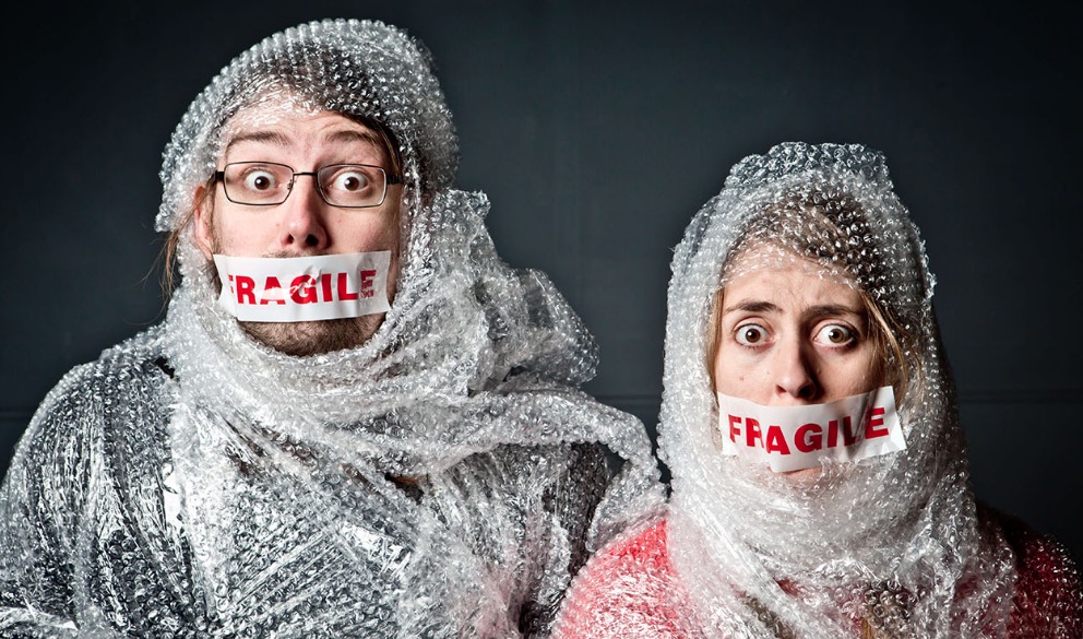 A male and female with Fragile Tape over their mouths and wrapped in Bubble Wrap