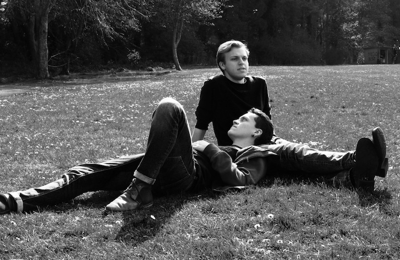 Two men lying together in a park