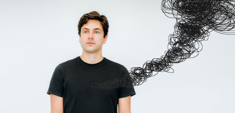 man in balck t shirt in front of white wall with black scribbles